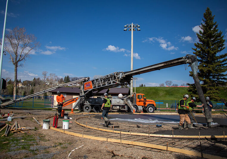 team of contractors using a telebelt to pour new concrete